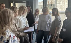 Susitikimo dalyviai stovi ratu ir diskutuoja.