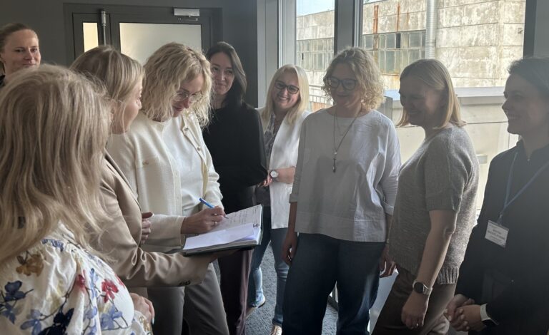 Susitikimo dalyviai stovi ratu ir diskutuoja.