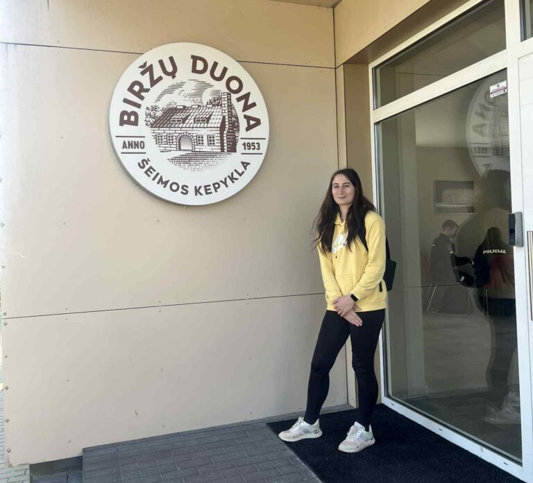 Istorijos herojė Dovilė stovi prie savo darbovietės "Biržų duona" durų.